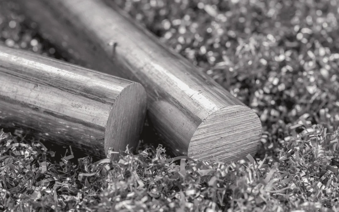 Close-up of raw cylindrical aluminum rods resting on metallic machining chips